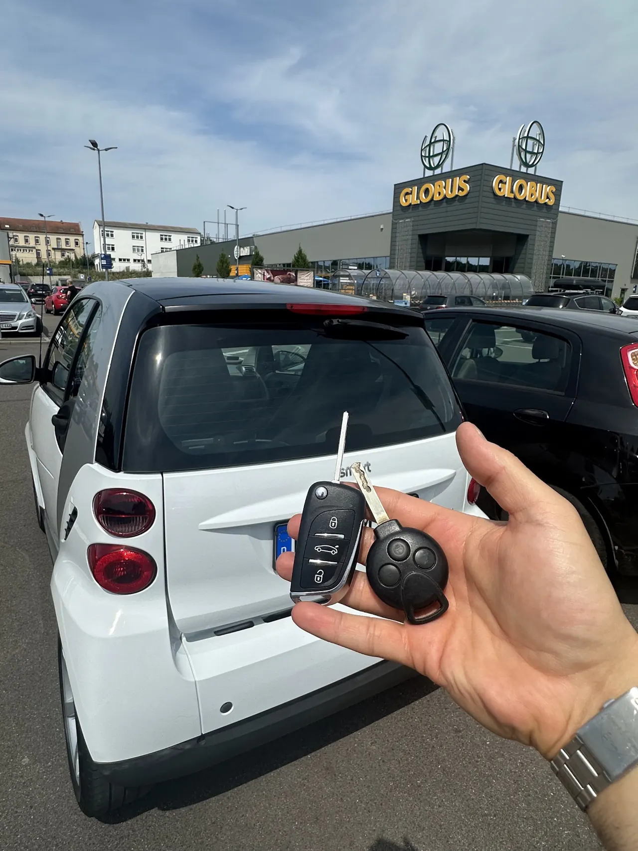 Neuer Klappschlüssel vor einem Smart am Globus