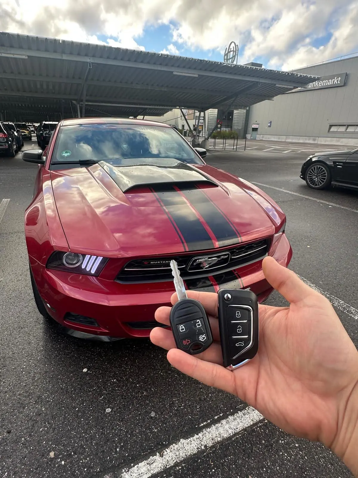 Zwei neue Funkschlüssel vor einem roten Ford Mustang
