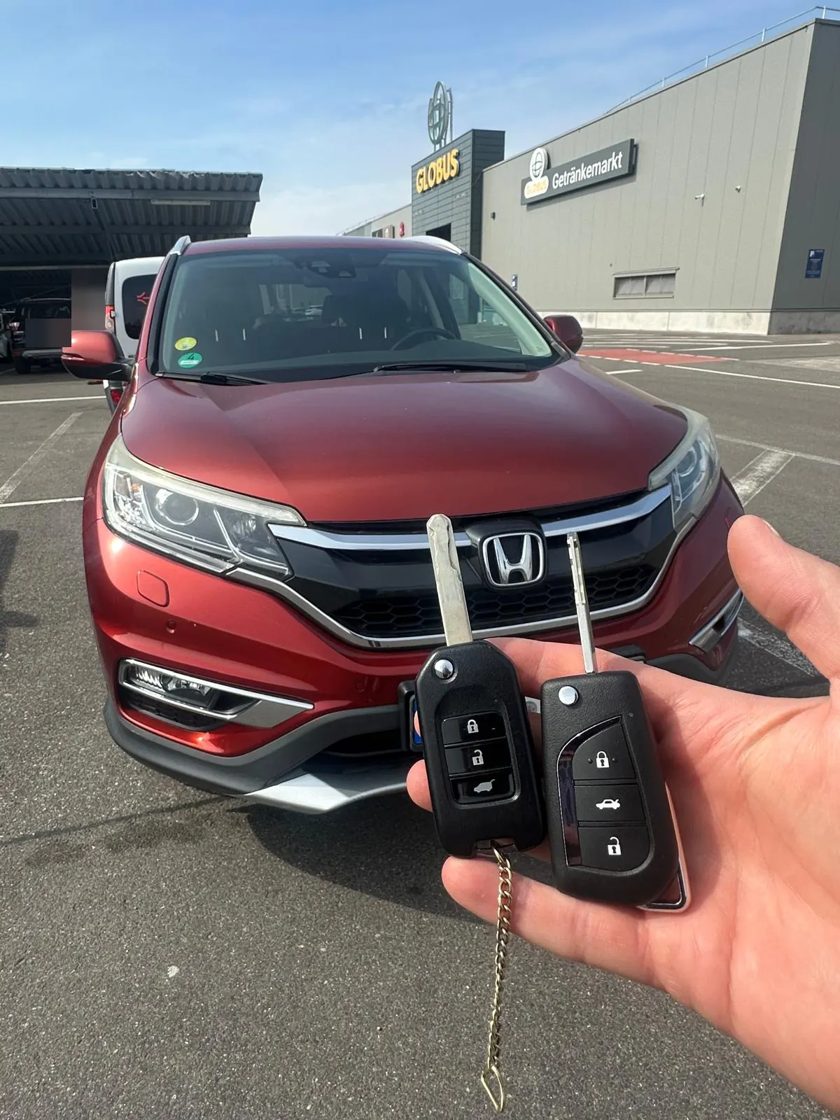 Zwei neue Klappschlüssel vor einem roten Honda CR-V am Globus