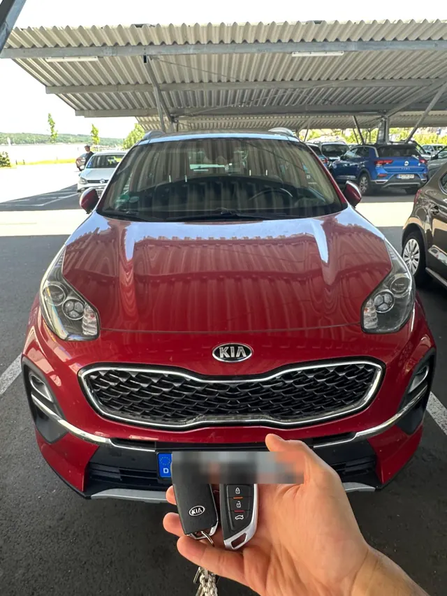 Zwei Kia-Schlüssel vor einem roten Kia Sportage
