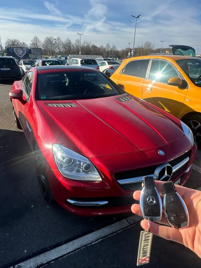 Zwei Mercedes-Schlüssel vor einem roten Mercedes SLK