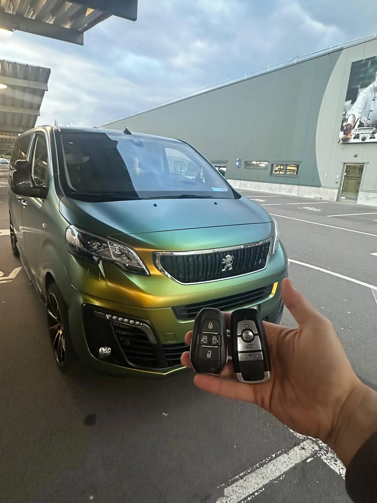 Zwei neue Funkschlüssel vor einem Peugeot-Bus mit Farbwechsel-Folie