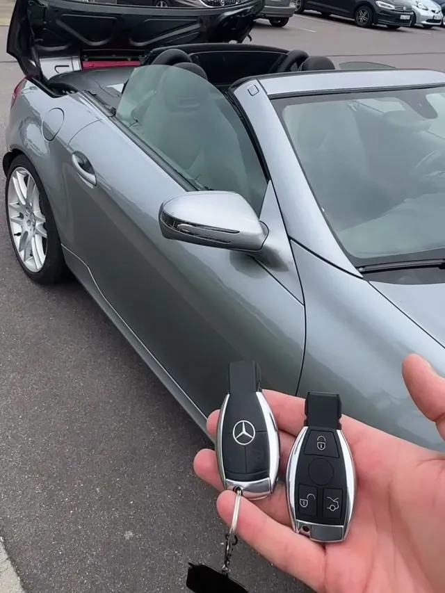 Zwei Mercedes-Schlüssel vor einem silbernen Mercedes SLK Roadster