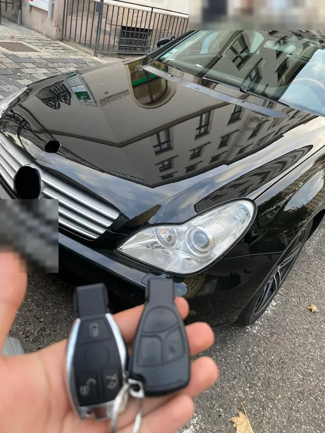 Zwei Mercedes-Schlüssel vor einem schwarzen Mercedes CLS